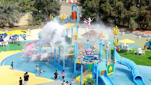 Un parc aquatique doté d’une vaste aire de jeux aquatiques, de toboggans et d’un panneau accueillant les visiteurs.