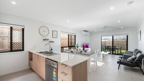 Une cuisine moderne dotée d’un îlot central, d’un coin repas avec une table et des chaises, et d’un espace détente avec un canapé.