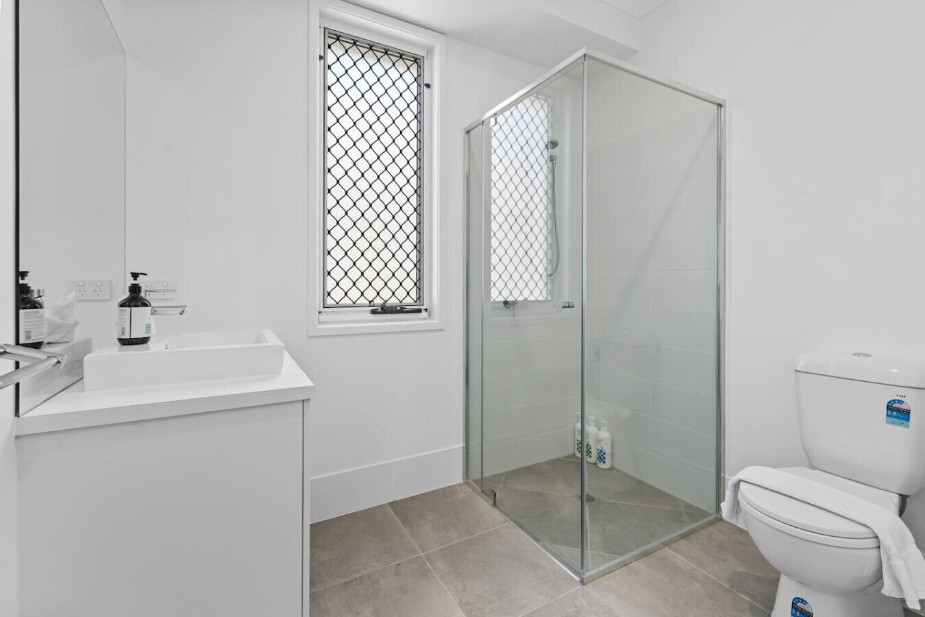 Ein modernes Badezimmer mit Duschkabine aus Glas, einem weißen Waschbecken und einer Toilette.