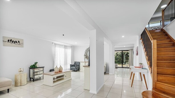 A spacious living area with a staircase, a sofa, a coffee table, and a chair. - Peaceful 4BR Retreat in Leafy Forest Lake Setting (Forest Lake)
