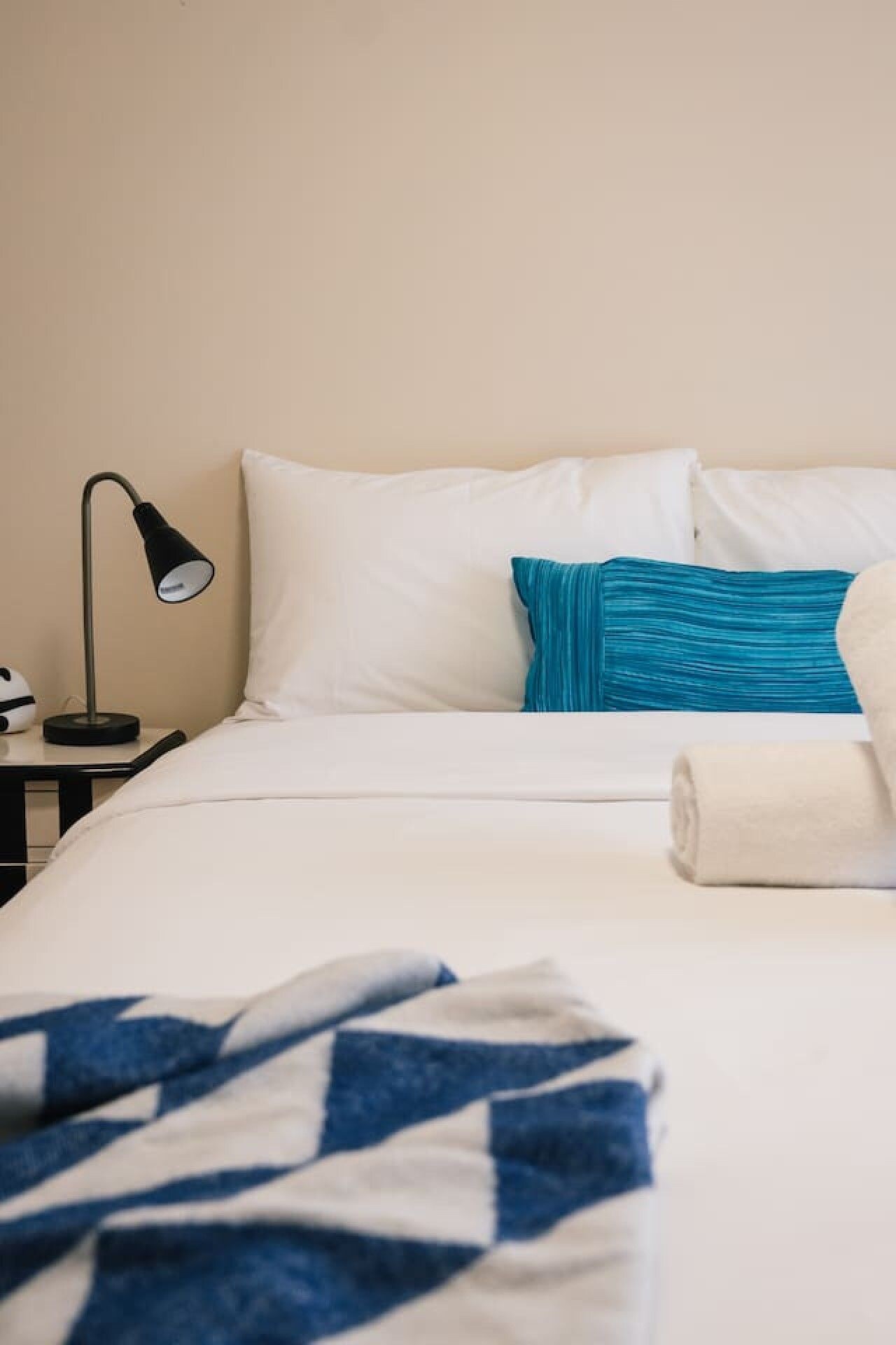 Une chambre d’hôtel avec un lit, une table de chevet avec une lampe et une serviette enroulée.