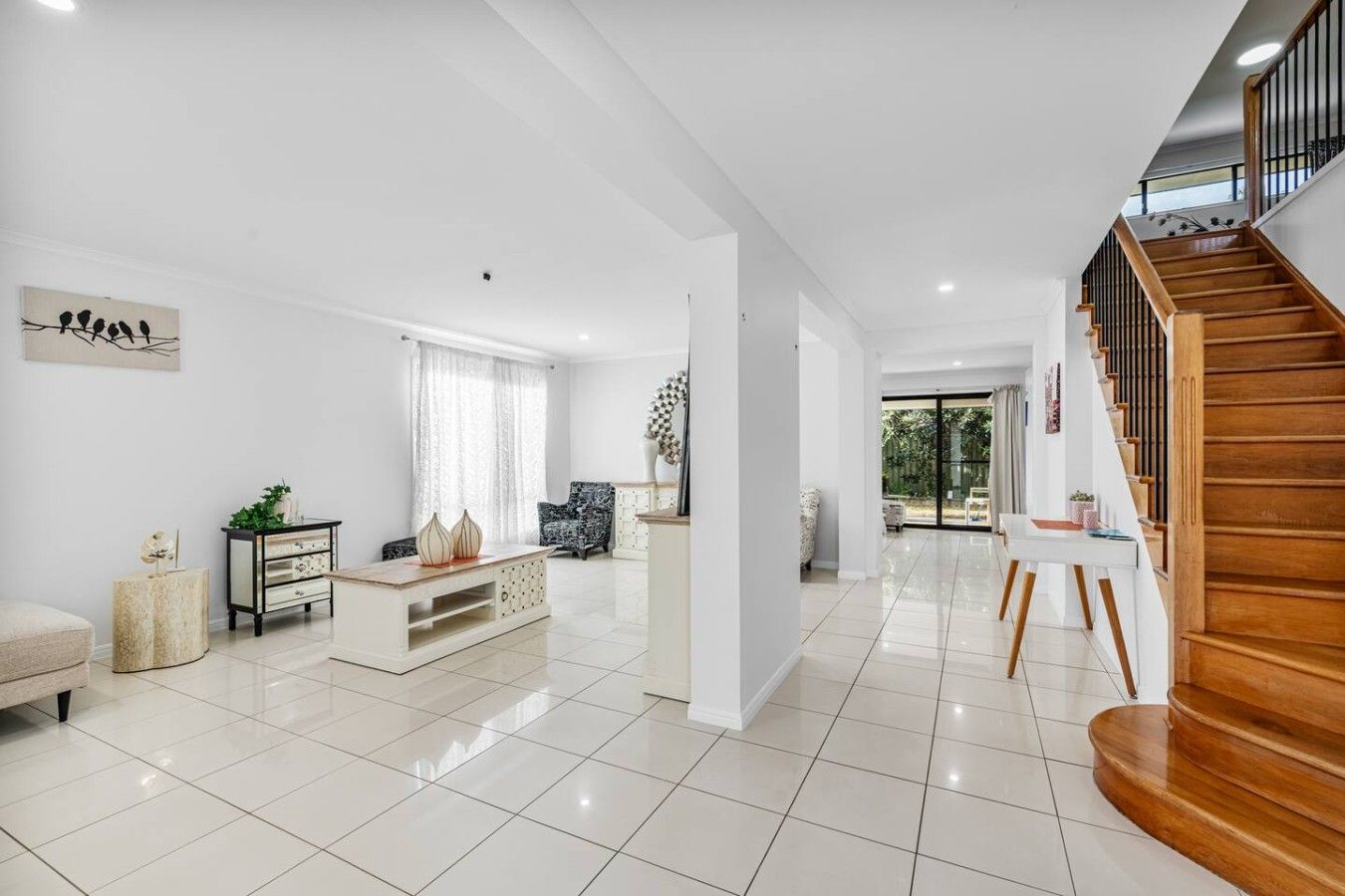 A spacious living area with a staircase, a sofa, a coffee table, and a chair.