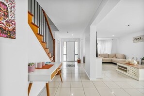 Un salon moderne avec un canapé, une table basse et un escalier menant à une autre pièce.