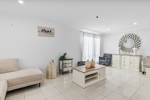 Een moderne woonkamer met een bank, salontafel, bijzettafeltje, kast en een kunstwerk aan de muur.