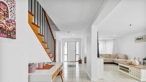 A modern living room with a sofa, coffee table, and a staircase leading to another room. - Peaceful 4BR Retreat in Leafy Forest Lake Setting (Forest Lake)