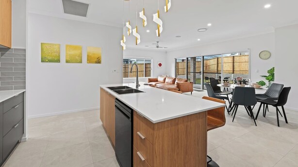 A modern kitchen with a central island, a dining area with a table and chairs, and a living area with a sofa.