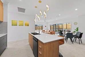A modern kitchen with a central island, a dining area with a table and chairs, and a living area with a sofa.