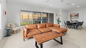 A modern living room with a leather sofa, a wooden coffee table, and a dining area with a table and chairs.