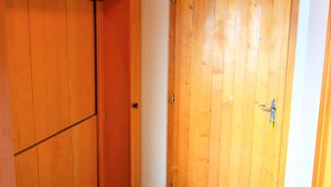 Une porte en bois avec une poignée en métal, un mur blanc et un plancher en bois.