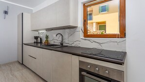 A modern kitchen with a marble backsplash, stainless steel appliances, and a window with a view of a building. - Holiday home Villa Vrbnik by Villas guide (Vrbnik)