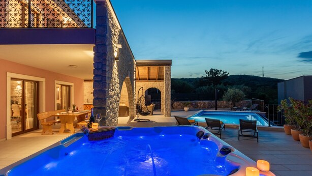 A pool area with a hot tub, outdoor seating, and a stone building. - Holiday home Villa Vrbnik by Villas guide (Vrbnik)