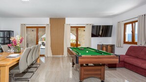 A pool table in a room with a dining area, a sofa, and a TV on the wall. - Holiday home Villa Vrbnik by Villas guide (Vrbnik)