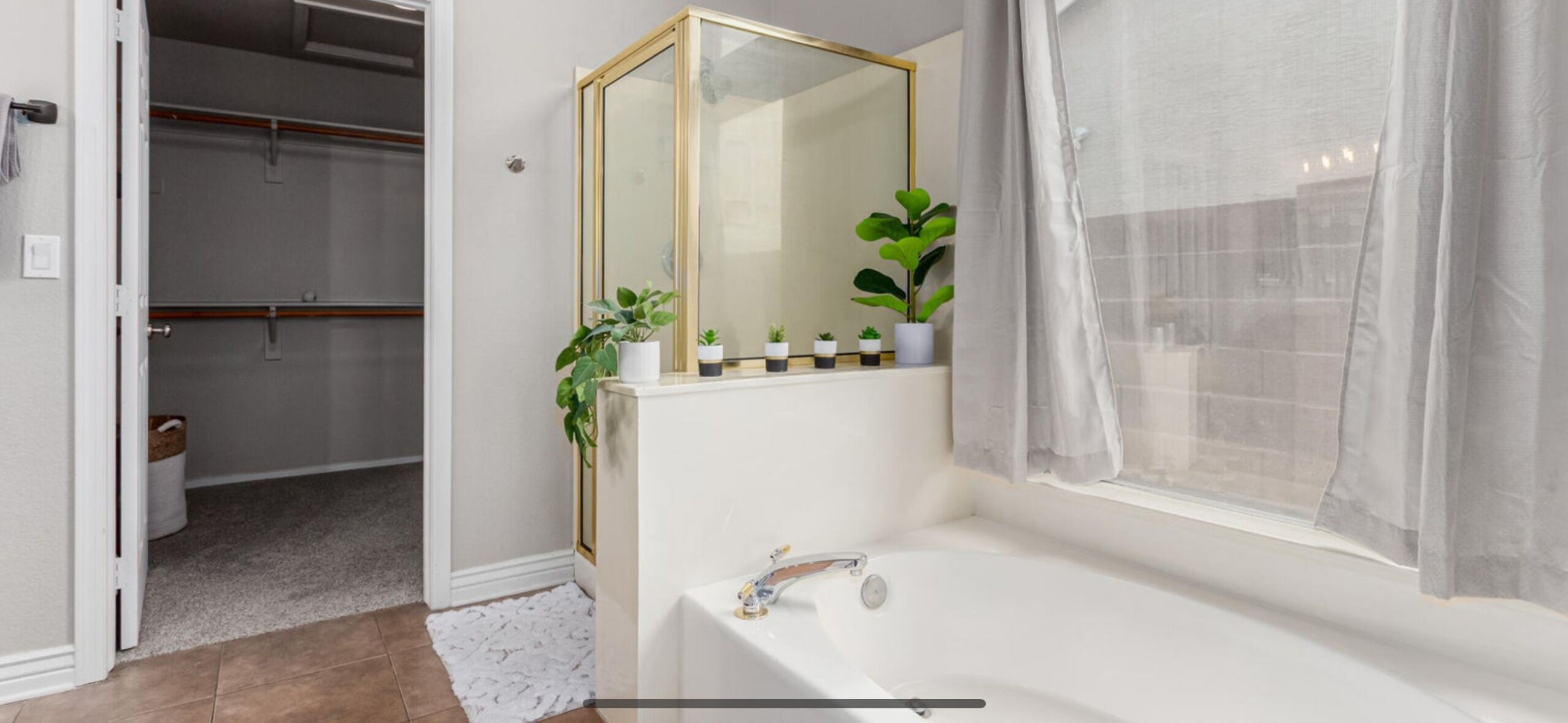 Un baño con bañera, espejo y ventana con cortina translúcida.