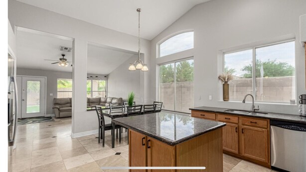 A spacious kitchen with a large island, wooden cabinets, and a dining area with a sofa and chairs.