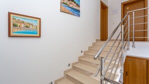 A staircase with a metal handrail, beige steps, and a wooden door with the number 7.