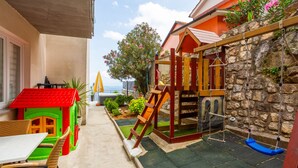 A children's play area with a slide, swing set, and a small house. - Apartman Zora 3 by Villas guide (Mošcenice)