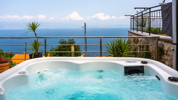 A hot tub with a view of the ocean, surrounded by plants and a balcony with a railing. - Apartman Zora 3 by Villas guide (Mošcenice)