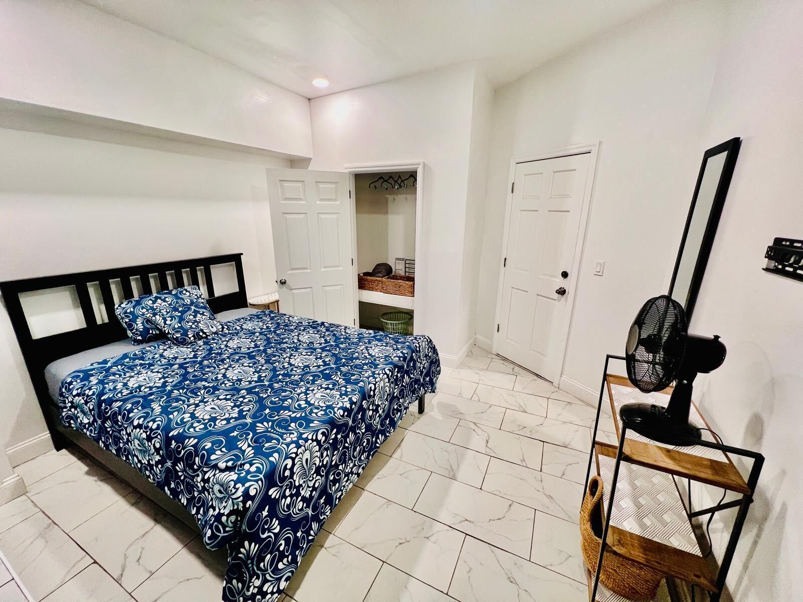 Ein Schlafzimmer mit einem Bett, einem Ventilator und einer Tür zu einem Badezimmer.