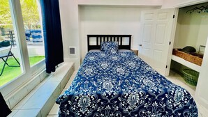 A bedroom with a large bed, a window with curtains, a door, and a small table with a basket. - 3-bedroom apartment in charming Philadelphia with WiFi, AC (Philadelphia)