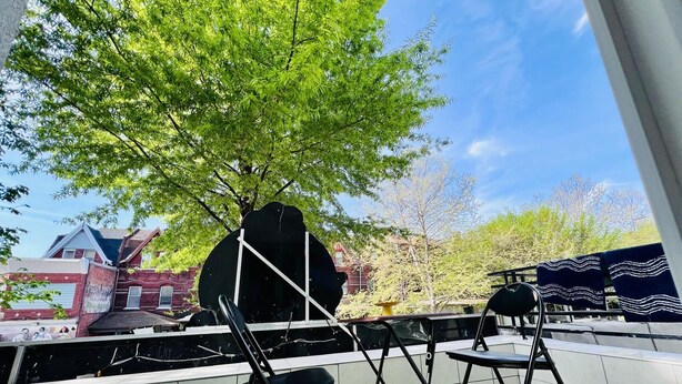 A patio with two black chairs, a grill, and a view of a brick building. - 3-bedroom apartment in charming Philadelphia with WiFi, AC (Philadelphia)
