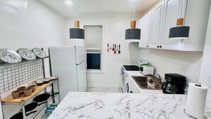 A modern kitchen with white cabinets, a marble countertop, and various appliances including a refrigerator, microwave, and coffee maker. - 3-bedroom apartment in charming Philadelphia with WiFi, AC (Philadelphia)