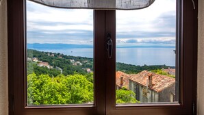 A view through a window with a door, overlooking a lake and a village with red-roofed buildings.