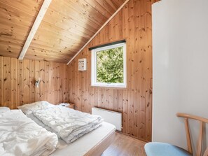 Puupaneloitu huone, jossa on sänky, ikkuna ja tuoli.