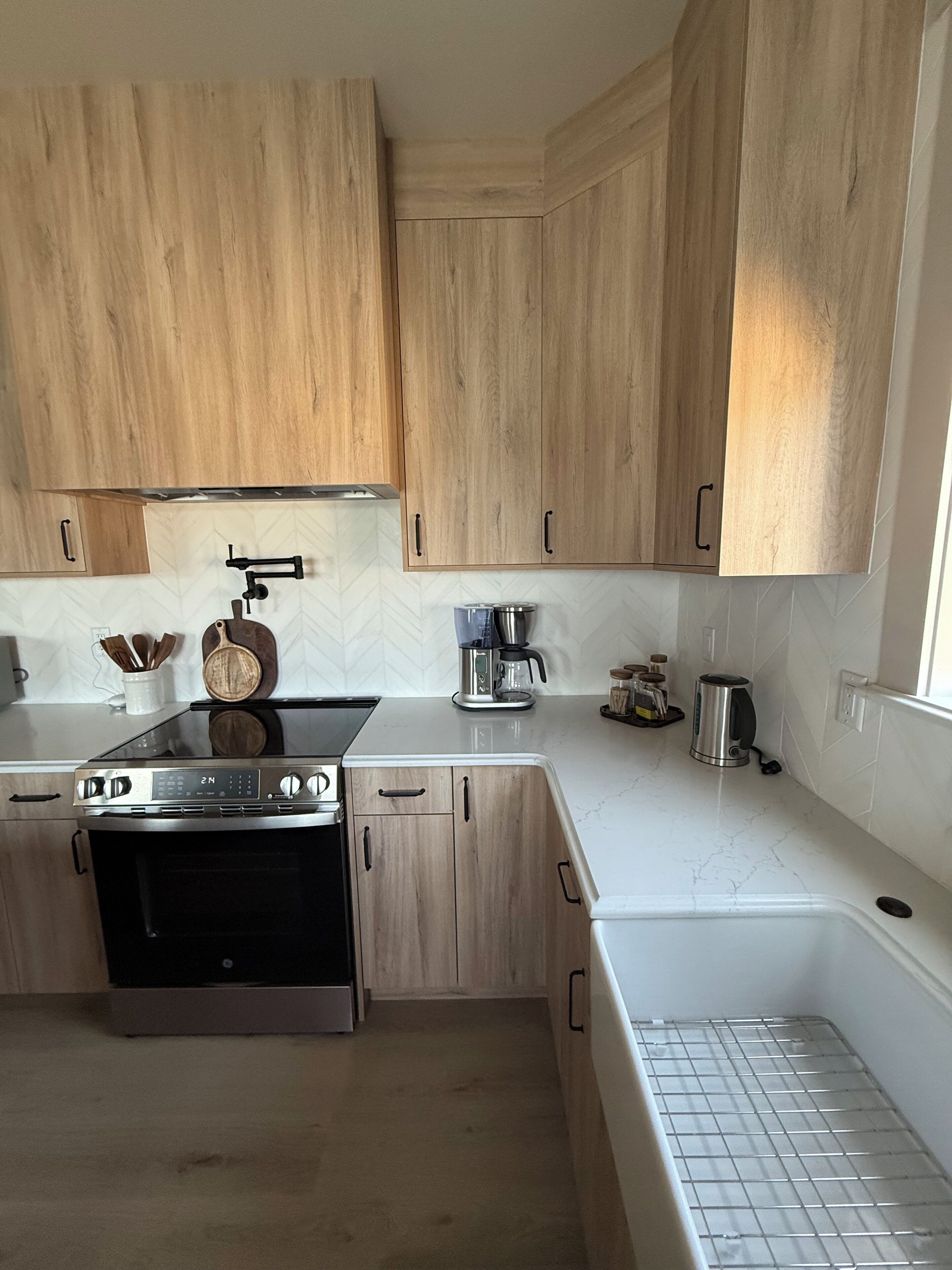 A modern kitchen with wooden cabinets, a stainless steel stove, and a coffee maker.