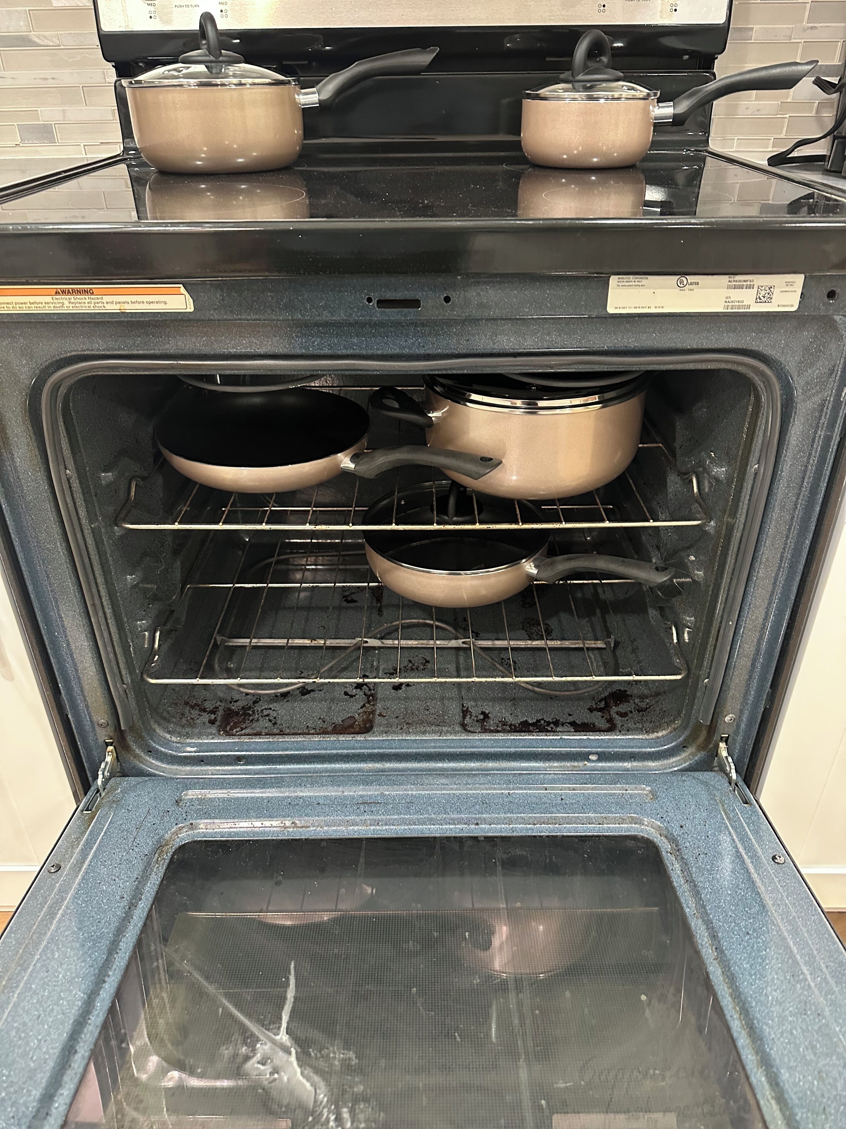 An open oven with pots and pans inside.