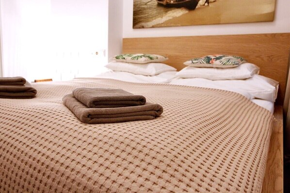 Un lit bien fait, avec une couvre-lit tissée, une tête de lit en bois et des coussins décoratifs.