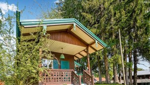 Ein Holzhaus mit Veranda, grünen Fensterläden und einer weißen Außenwand.