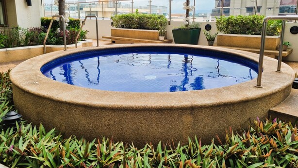 A rooftop pool with a circular shape, surrounded by plants and palm trees. - Simple & Clutter-Free 2BR, 1BA Condo in Quezon City, near Heart Center & NKTI (Quezon City)