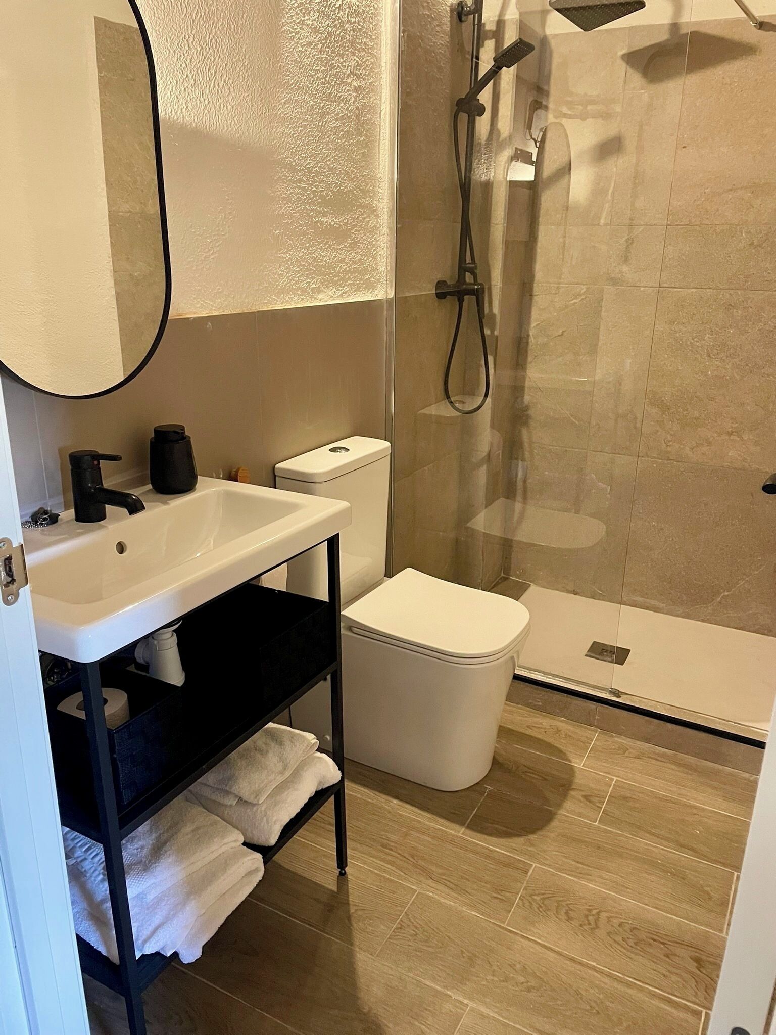 A modern bathroom with a white sink, black faucet, and a glass-enclosed shower.