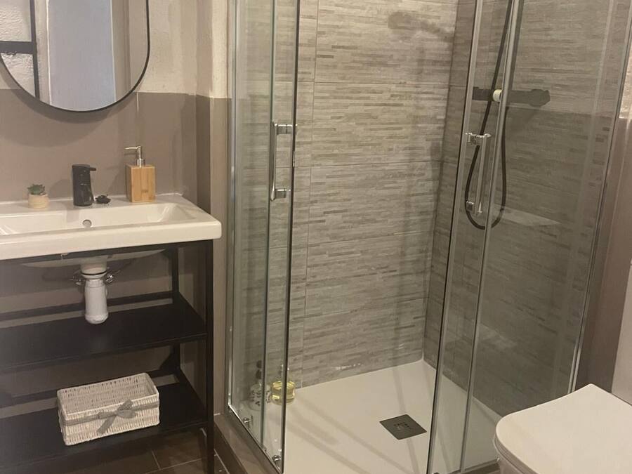 A modern bathroom with a glass-enclosed shower, a white sink, and a toilet.