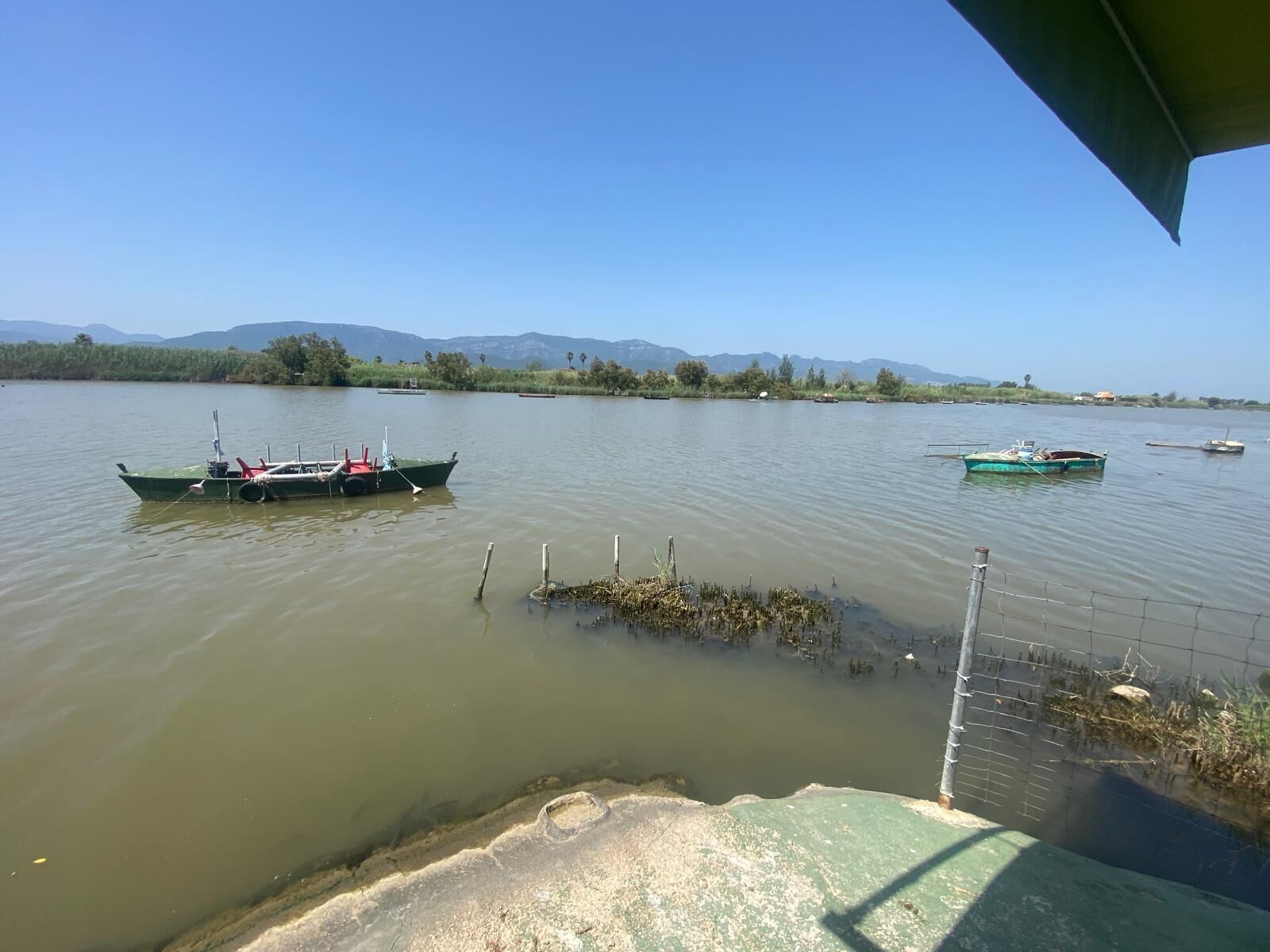 A calm lake with boats and a distant mountain range.