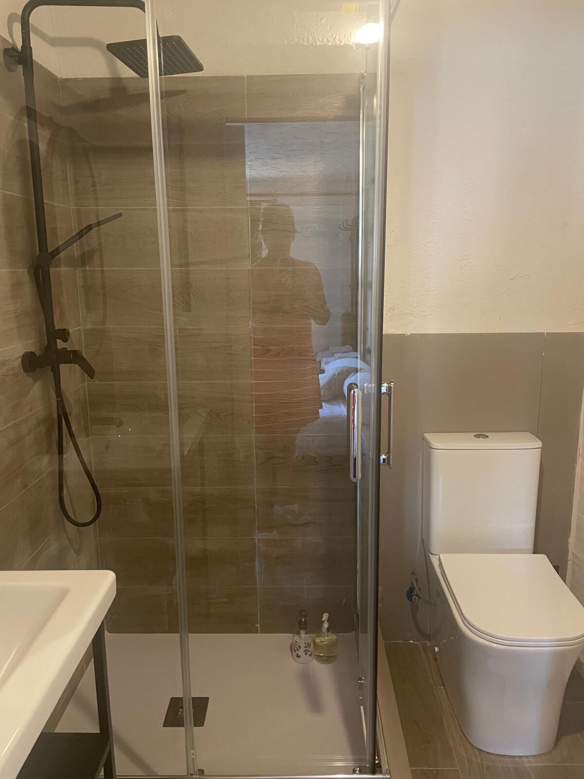 Un baño con ducha de vidrio, inodoro y lavamanos.