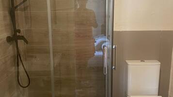 Un baño con ducha de vidrio, inodoro y lavamanos.