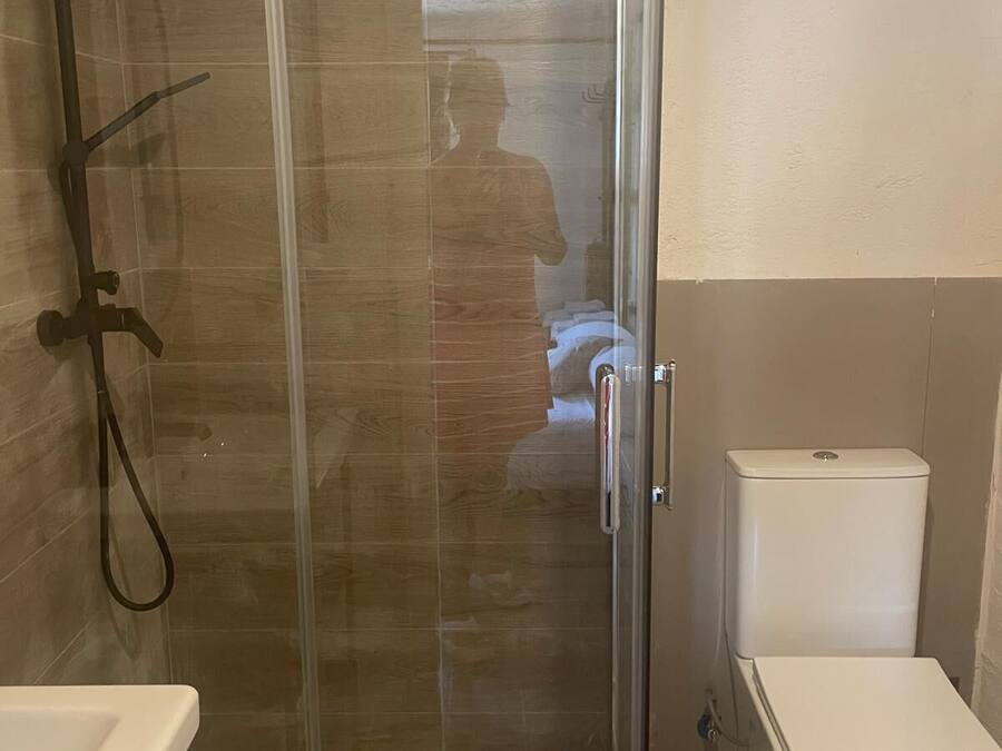 Un baño con ducha de vidrio, inodoro y lavamanos.