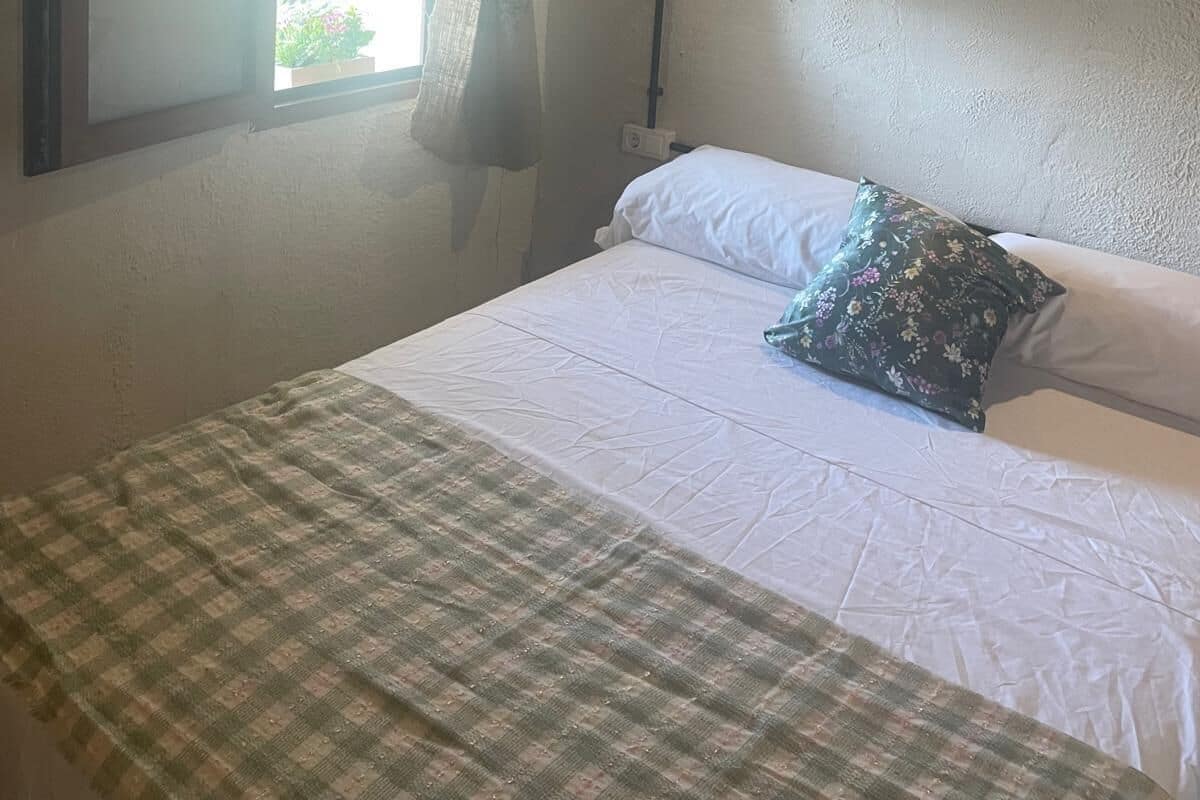 Ein Schlafzimmer mit Bett, einem Vorhangfenster, einem Bild an der Wand und einer Holzbalkendecke.