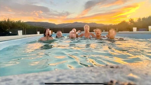En grupp människor i ett bubbelbad med utsikt över solnedgången.