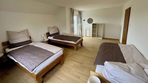 A room with two wooden beds, a small table, a mirror, and a wardrobe. - Vacation home at Vogelsang (Meschede)