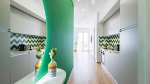 A modern kitchen with white cabinets, a green accent wall, and a zigzag patterned backsplash.