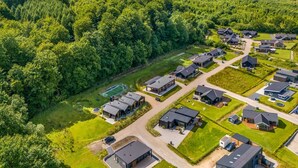 An aerial view of a residential area with modern houses, green lawns, and a forested hill in the background. - "Heidie" - 600m from the sea by Interhome (Sjølund)