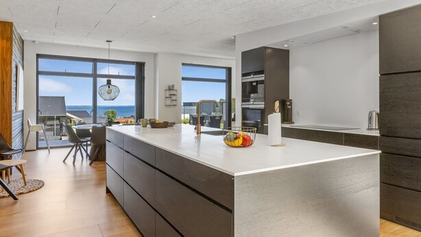 A modern kitchen with a large island, dark cabinetry, and a view of the sea through large windows. - "Heidie" - 600m from the sea by Interhome (Sjølund)