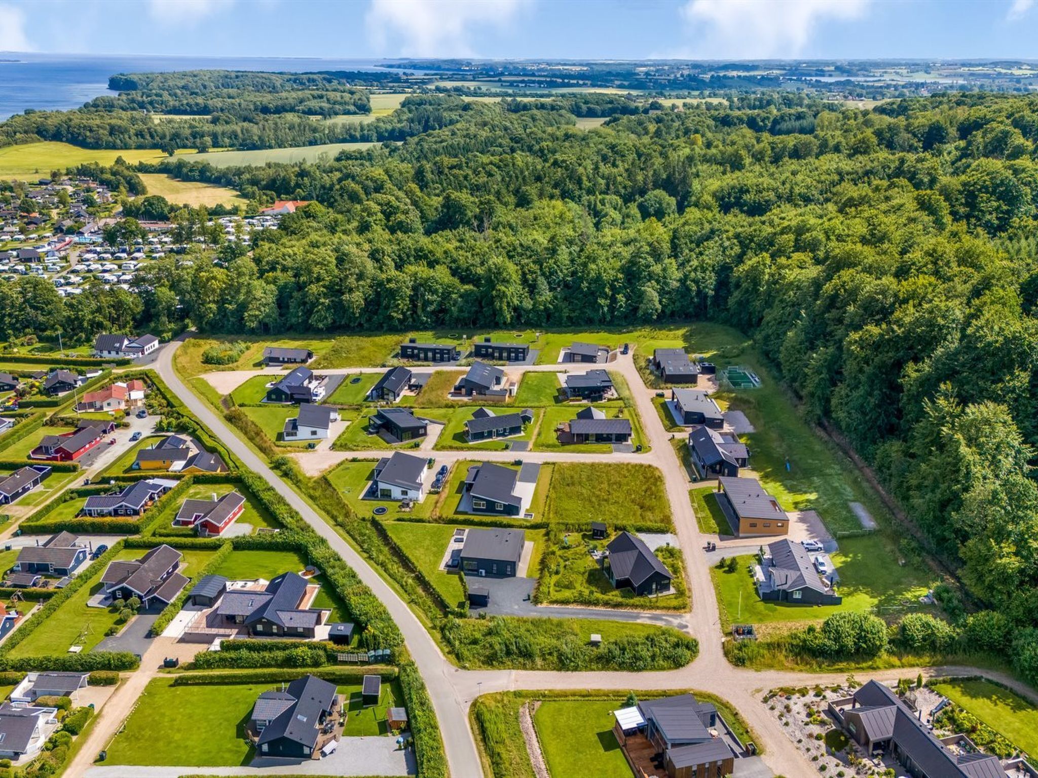 Vue aérienne d’un quartier résidentiel avec des maisons modernes, des pelouses verdoyantes et un ciel dégagé.