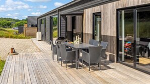 A modern outdoor patio with a wooden deck, a table with chairs, and a grill. - "Heidie" - 600m from the sea by Interhome (Sjølund)