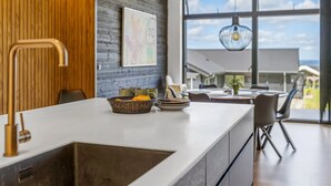 A modern kitchen with a large island, wooden paneling, and a view of the outdoors through large windows. - "Heidie" - 600m from the sea by Interhome (Sjølund)