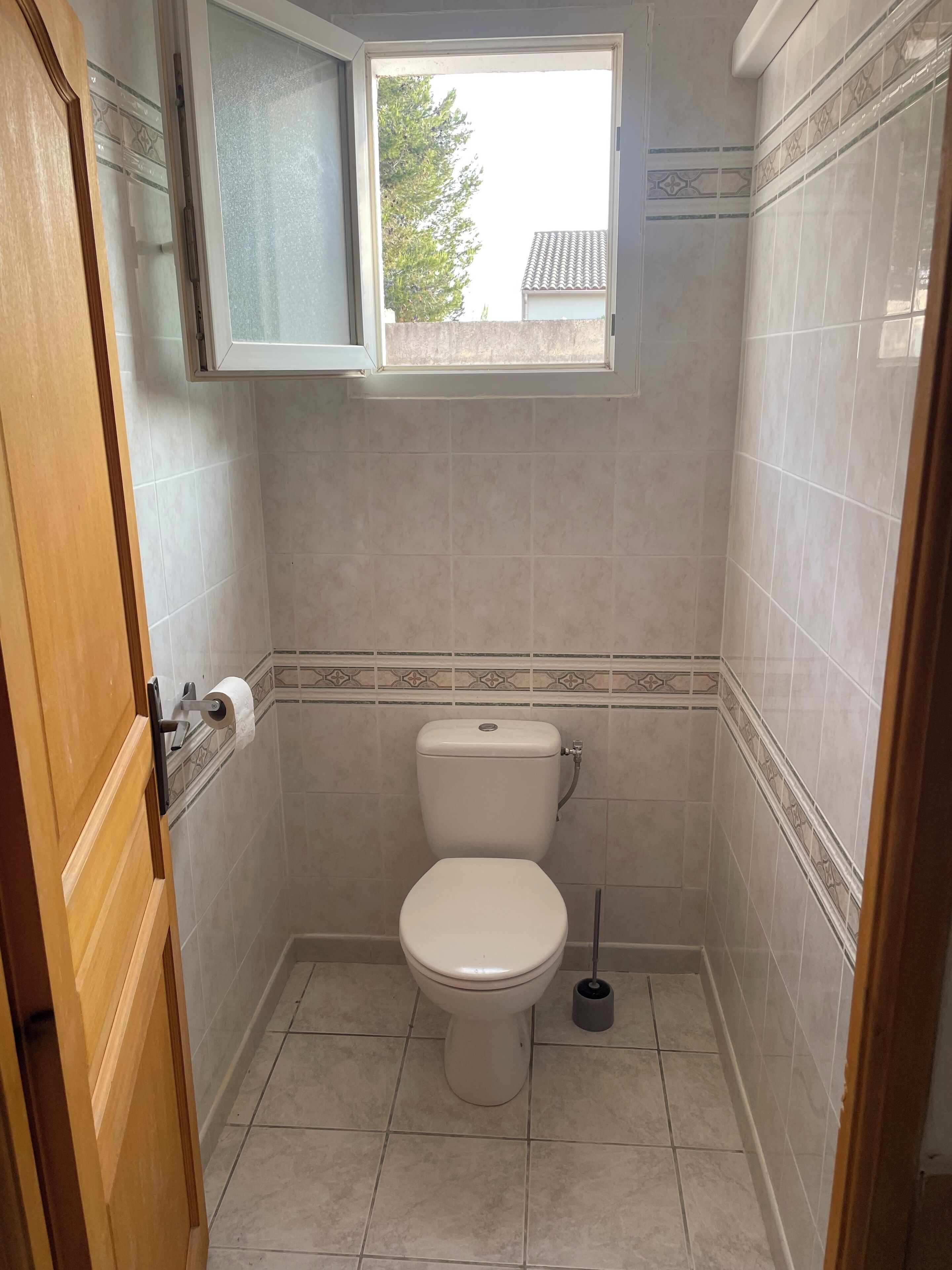 Un baño pequeño con inodoro, ventana y puerta.