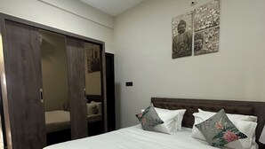 Een slaapkamer met een groot bed, een kledingkast en een muur met decoratieve kunstwerken.