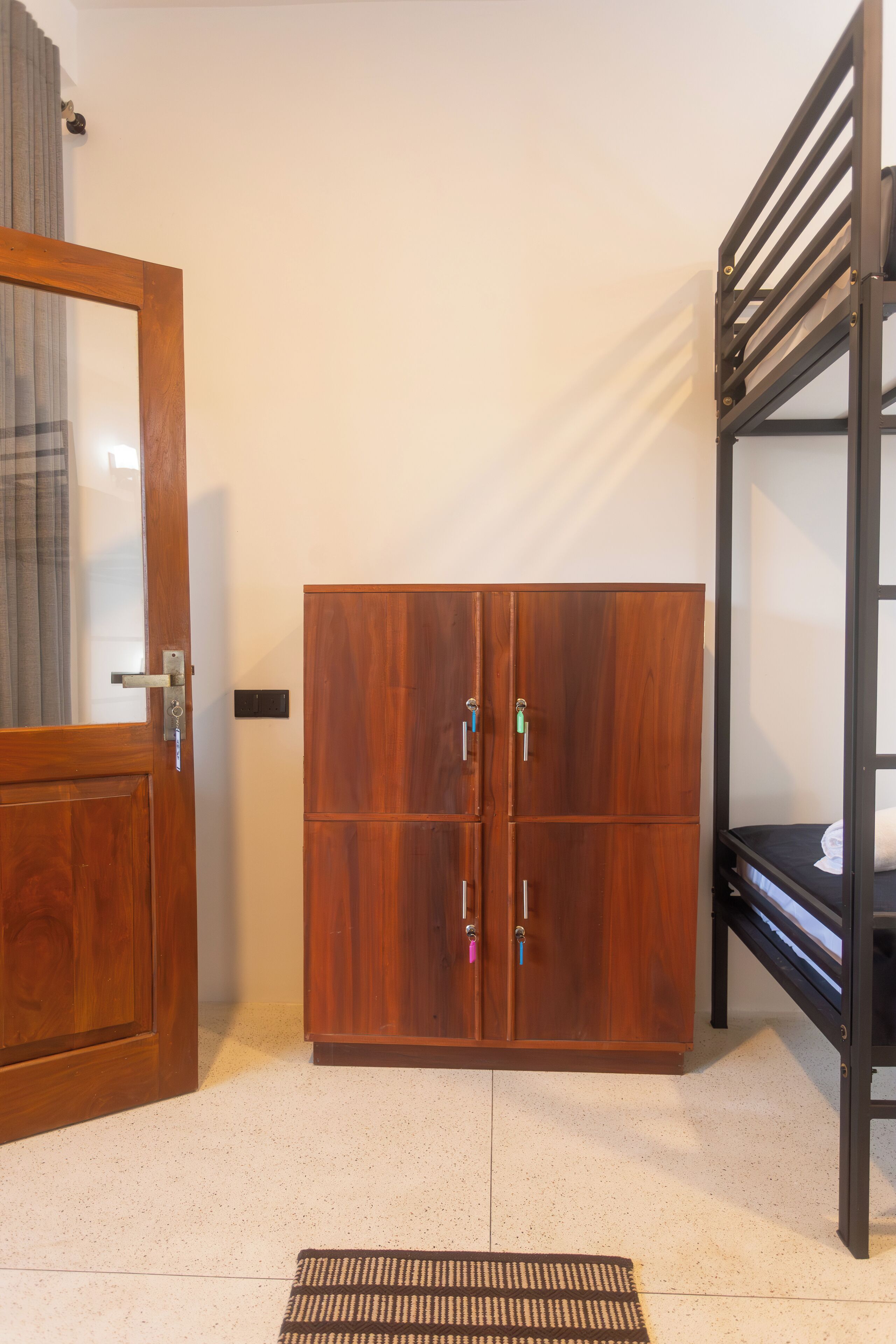 A room with a wooden wardrobe, a bunk bed, and a door with a mirror.